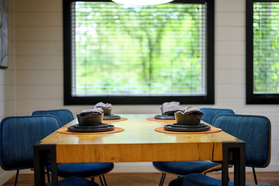 Gather around this inviting dining table, where your morning coffee or evening meal feels even better with peaceful garden views framing every moment. The cozy seating and natural light make it your perfect spot to unwind.