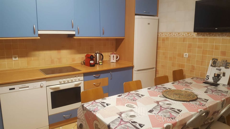 Kitchen with dining table, TV, oven and cooking utensils