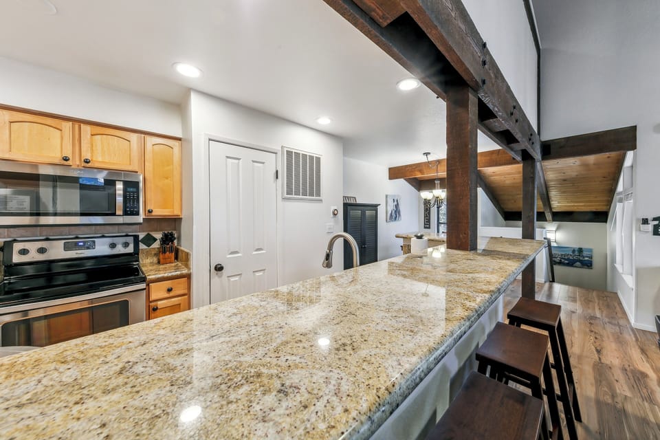Your fully-equipped kitchen features granite countertops, modern appliances, and rustic wooden beams for cooking and gathering together.