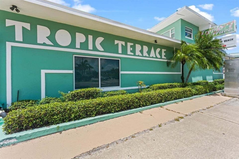 Tropic Terrace — a Treasure Island landmark for 50+ years. This retro Old Florida resort wraps around a lush tropical courtyard with a sparkling pool, just steps from the Gulf.