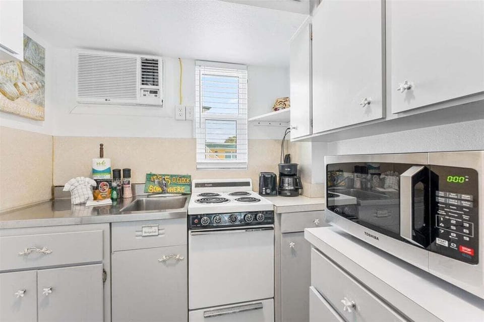 Bright studio space with a queen bed, TV, window AC, and a twin sleep sofa for additional sleeping — a cheerful coastal retreat close to the sand.