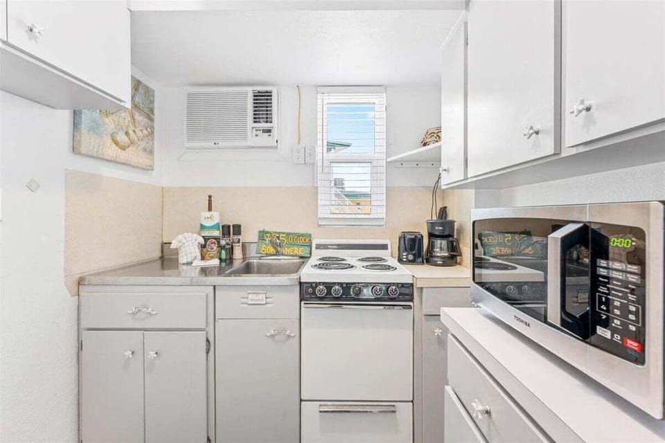 Bright studio space with a queen bed, TV, window AC, and a twin sleep sofa for additional sleeping — a cheerful coastal retreat close to the sand.