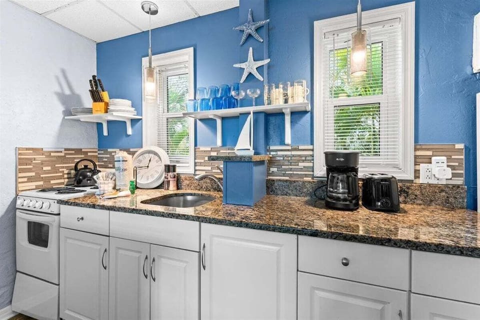 Fully equipped kitchen with granite counters, stove, microwave, fridge, and coffee maker — everything you need for a home-cooked meal.