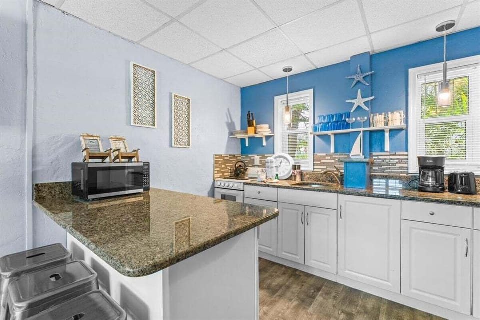 Fully equipped kitchen with granite counters, stove, microwave, fridge, and coffee maker — everything you need for a home-cooked meal.