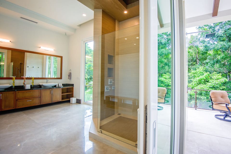 Downstairs Master Bathroom with rainforest view and balcony outside.