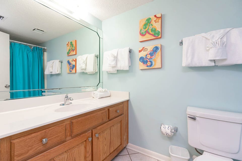 Refresh in the guest bathroom, featuring a spacious vanity, colorful artwork, and neatly arranged towels
