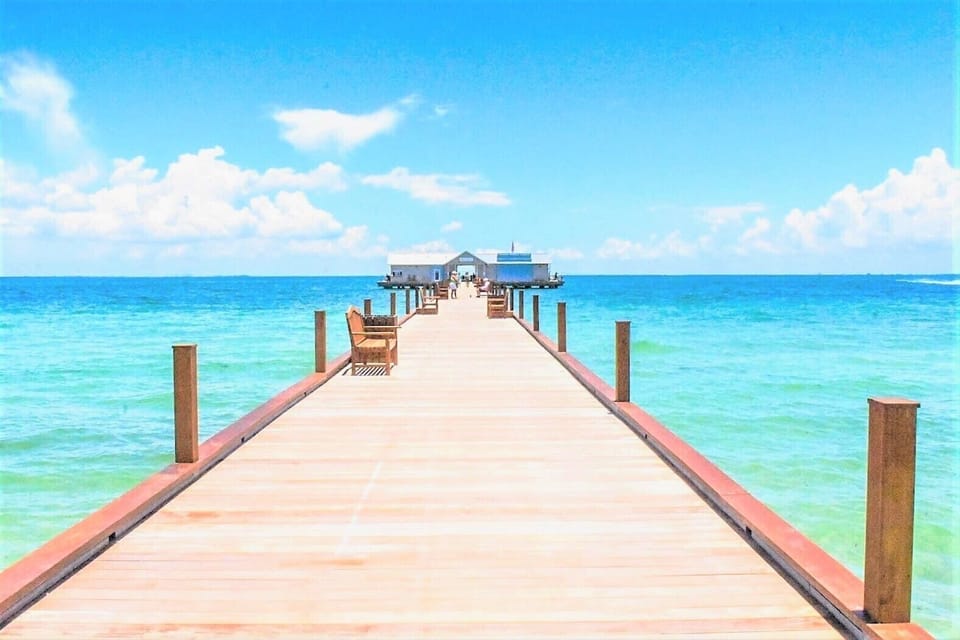 Wooden pier extending over clear Gulf waters toward a covered pavilion at the end