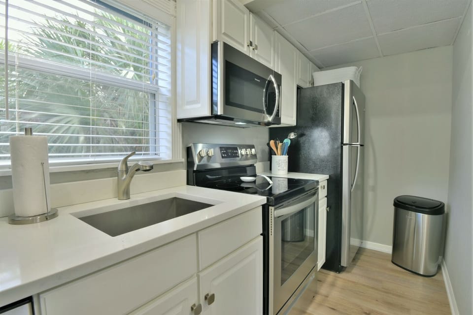 Kitchen with white cabinets, stainless steel microwave, range, refrigerator, and sink area