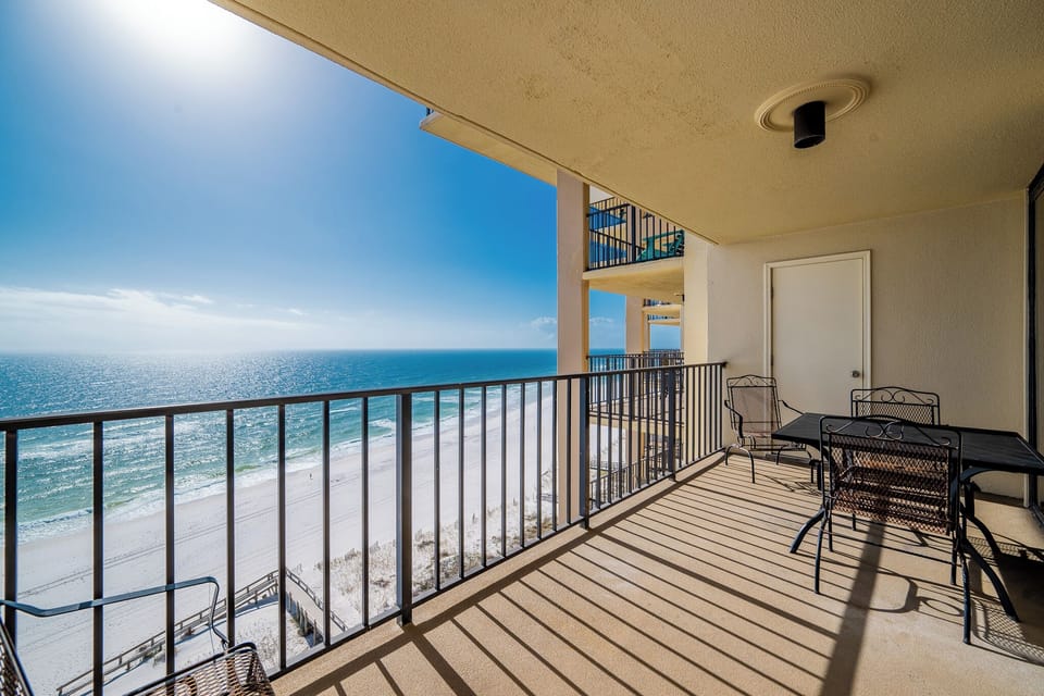 Enjoy the beautiful beach view from this balcony, featuring a table and chairs for relaxation