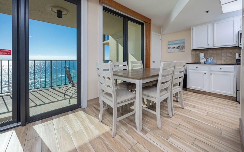 This dining area features a stylish table with six chairs, complemented by a bright beach view through large sliding doors