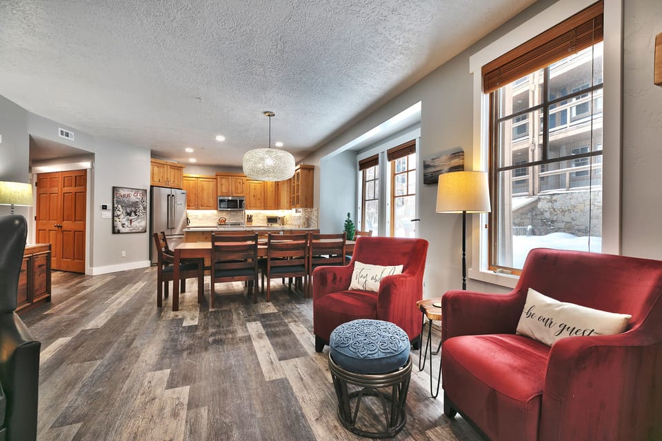 Red accent armchairs between the living room and dining room with blue foot stool