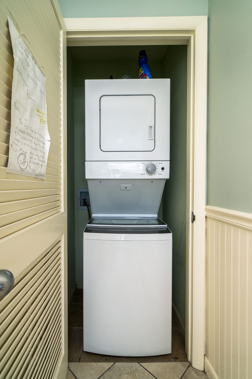 Laundry with stacked washer and dryer located behind closet door