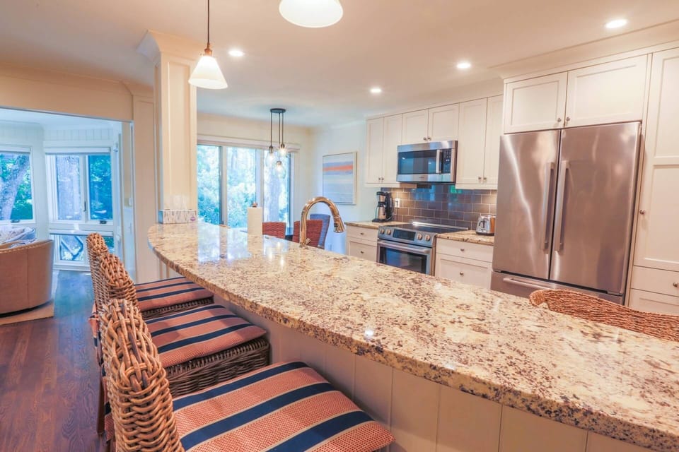 The curved breakfast bar with granite countertops separates the kitchen from the living room.