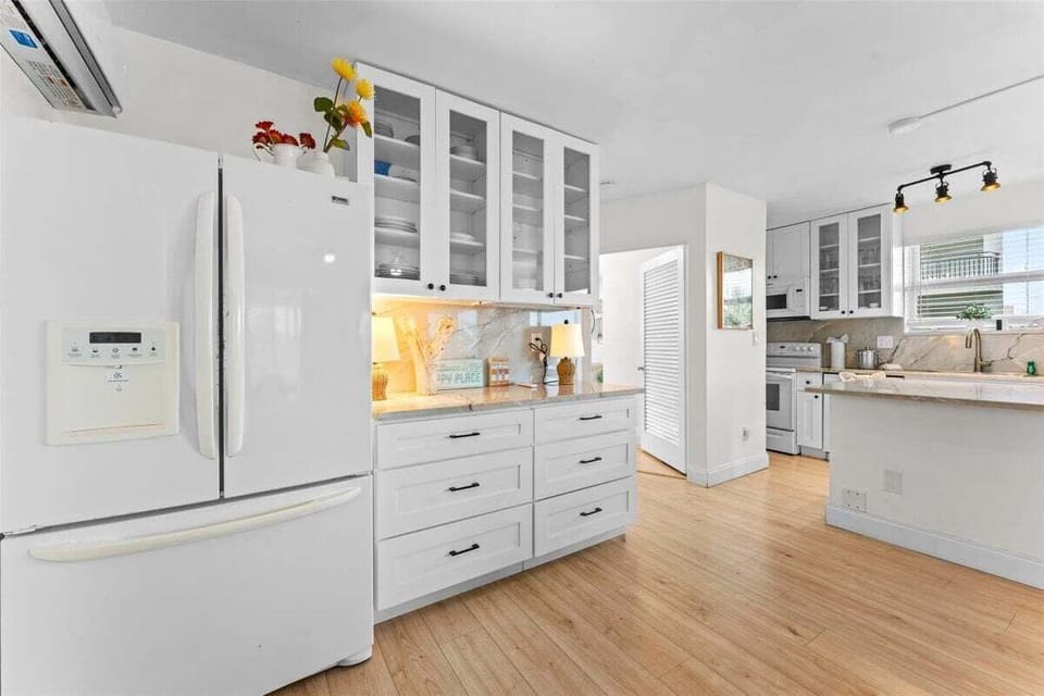 Fully equipped kitchen with granite counters, white appliances, dishwasher, electric range, microwave, and a large island — plenty of space for cooking and gathering.