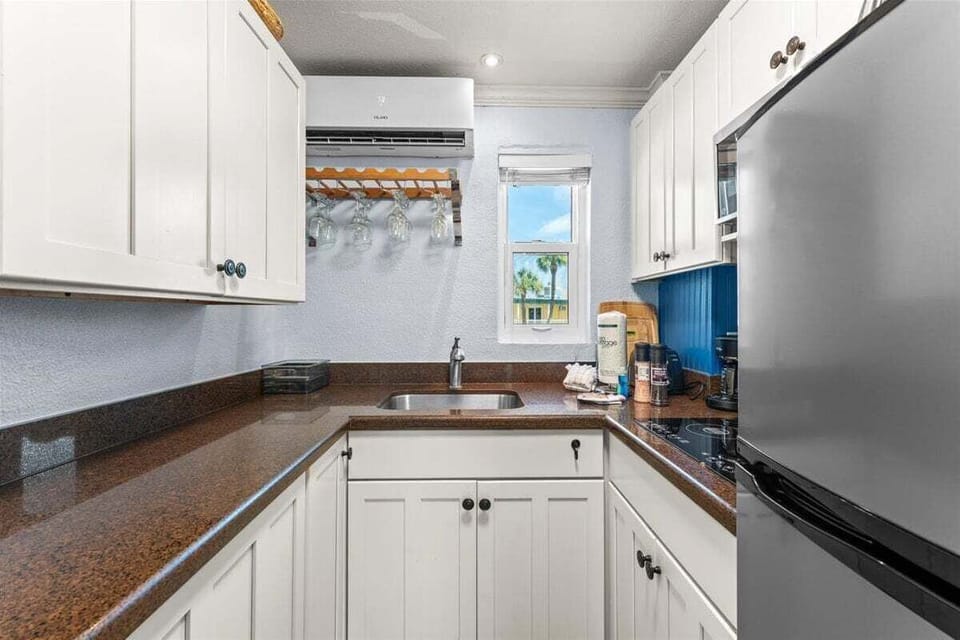Compact kitchen with a stainless fridge, induction cooktop, microwave, and coffee maker — everything you need for easy meals during your stay.