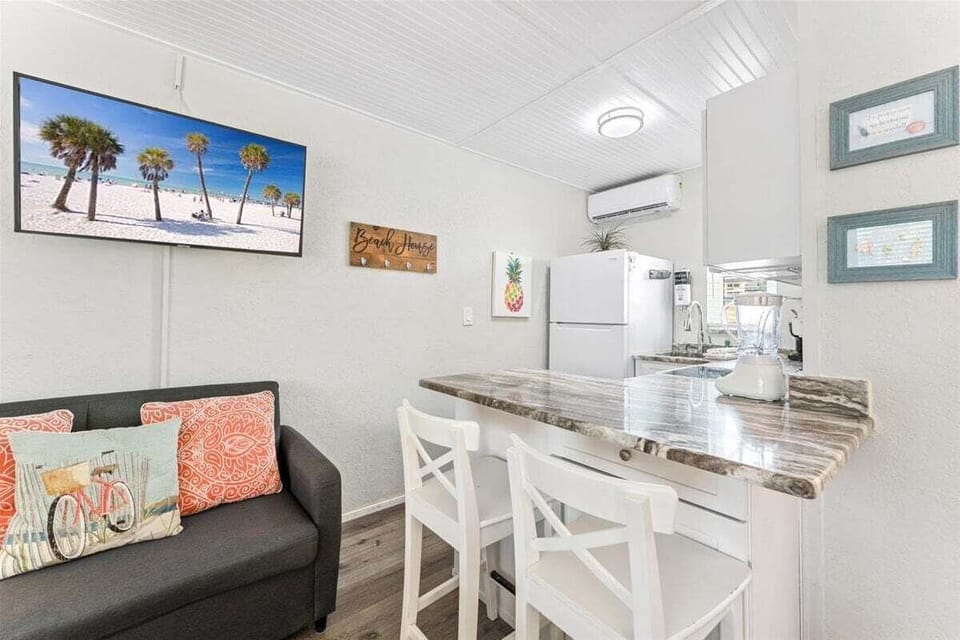 Fully equipped kitchenette with granite counters, white appliances, microwave, electric range, and bar seating for two — everything you need for a home-cooked meal.