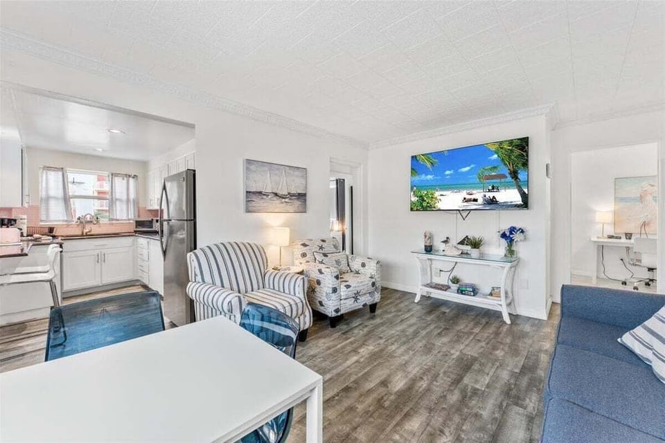 Bright, open living room with smart TV, sofa bed, coastal décor, and a dining area — a comfortable space to relax or gather after a day at the beach.