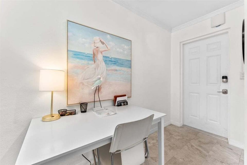 A bright dedicated workspace with a desk and coastal artwork — perfect for remote work or planning your next beach adventure.
