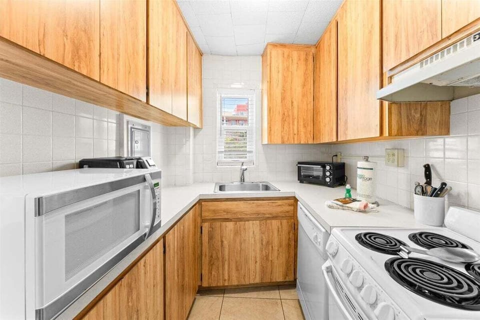 Fully equipped kitchen with wood cabinetry, stove, dishwasher, microwave, fridge, and coffee maker — everything you need for a home-cooked meal.