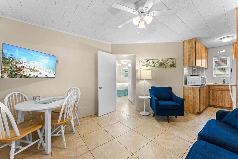 Bright living room with smart TV, ceiling fan, AC unit, and dining table — a comfortable space to relax after a day at the beach.