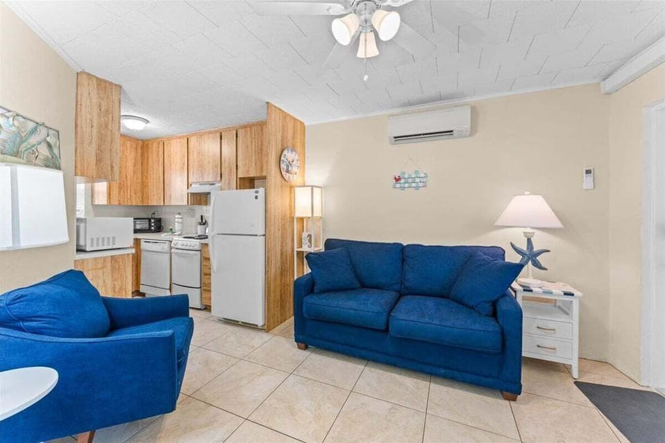 Bright living room with smart TV, ceiling fan, AC unit, and dining table — a comfortable space to relax after a day at the beach.