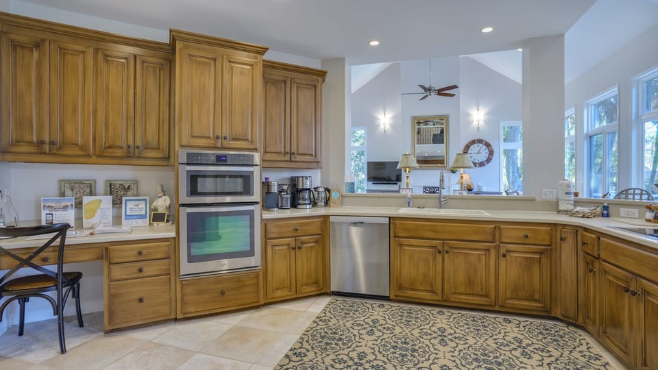 Generous counter space and thoughtful storage make meal prep effortless, while large windows frame tranquil wooded views that bring natural light into the room.