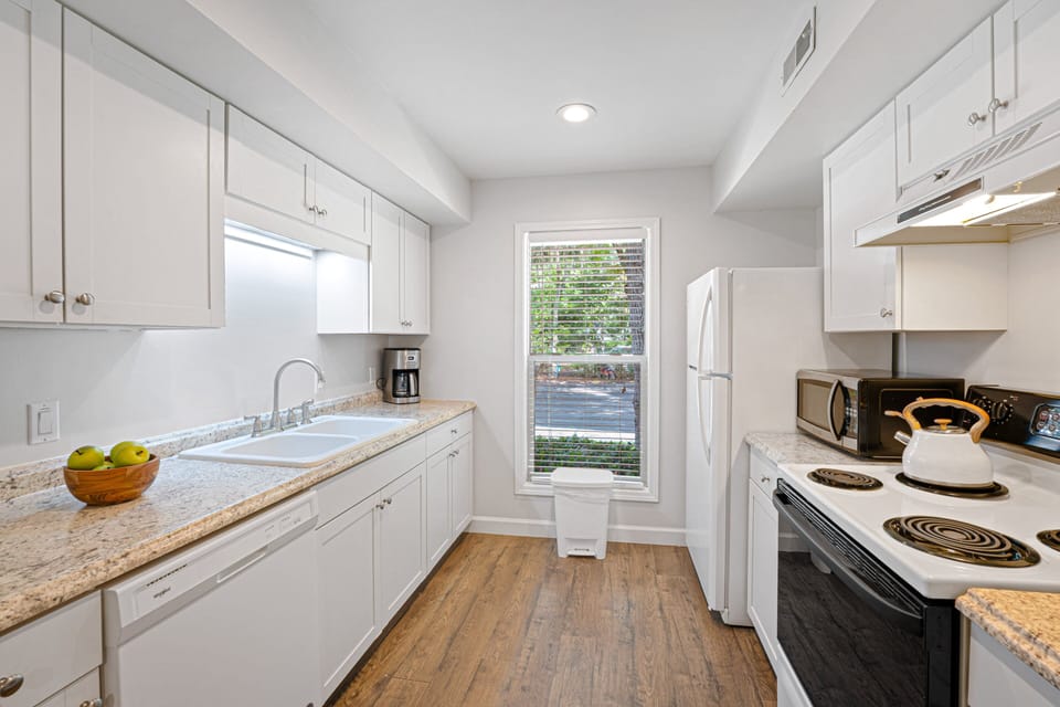 Bright, efficient kitchen with crisp white cabinetry, granite countertops, and a full suite of appliances.