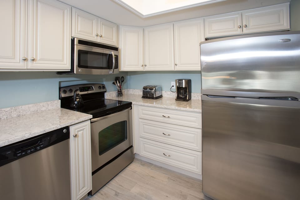 The kitchen features a spacious countertop, white cabinetry, and a full suite of appliances—providing plenty of room for meal prep and casual dining at the breakfast bar.