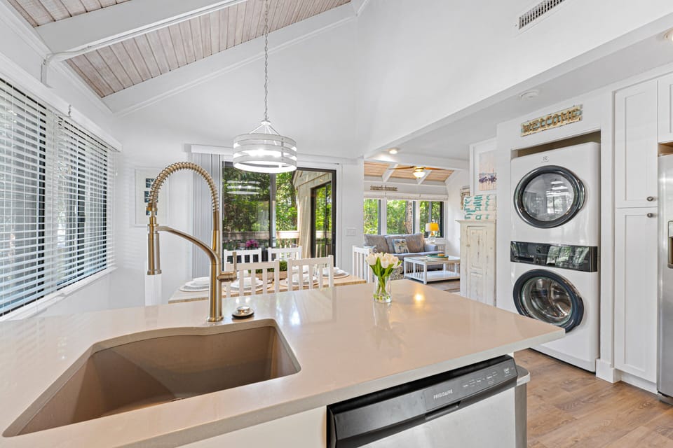 Gleaming quartz countertops, custom white cabinetry, stainless steel appliances, and a large center island provide plenty of space for preparing meals.