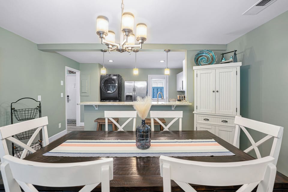 A charming dining nook with coastal hues and warm lighting, offering a welcoming spot to gather and enjoy meals just steps from the open kitchen and breakfast bar.