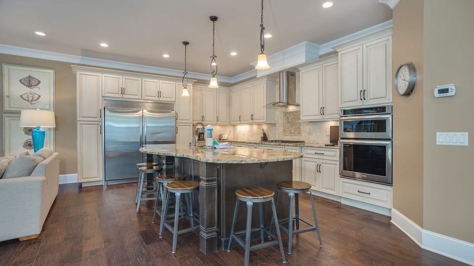 High-end stainless steel appliances—including a double oven, gas cooktop, and oversized refrigerator—make meal preparation effortless.