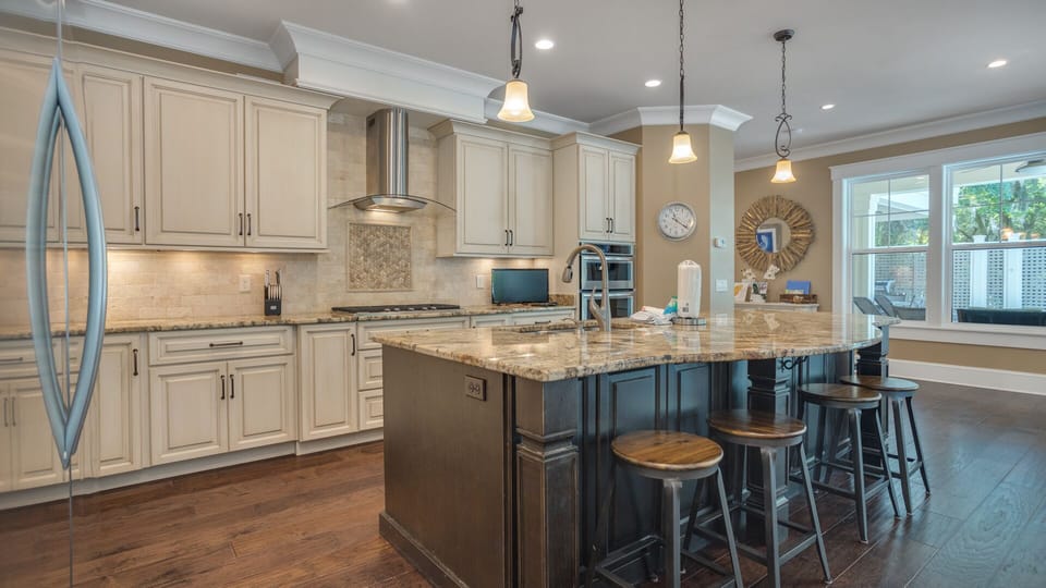 Pendant lighting and warm hardwood floors add charm and sophistication, while abundant storage and ample workspace ensure everyday convenience.