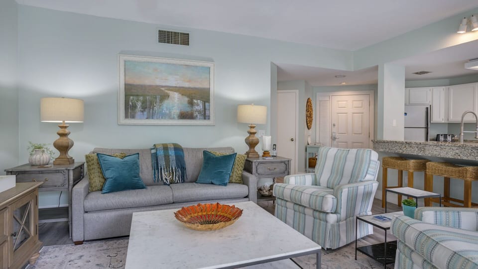 Soft, beach-inspired tones, wide plank flooring, and large windows create an airy feel filled with natural light.
