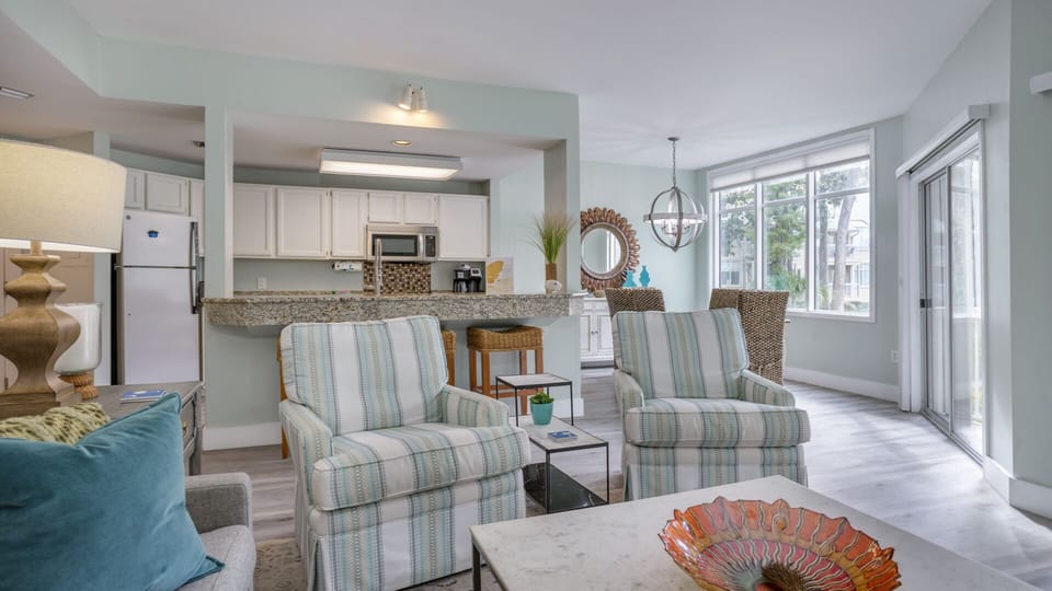The living space flows seamlessly into the dining area and kitchen, featuring a breakfast bar with seating—ideal for casual meals or entertaining.