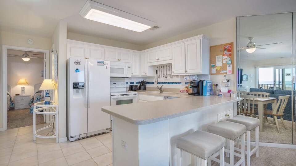 This bright, open kitchen is designed for easy vacation living. White cabinetry and ample counter space keep everything light and functional.