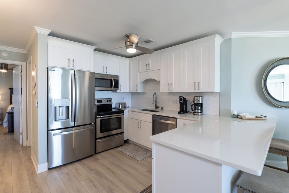 This beautifully updated kitchen showcases crisp white cabinetry, sleek quartz countertops, and stainless-steel appliances, creating a bright and polished cooking space.