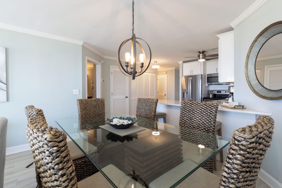 This inviting dining area offers a perfect blend of style and function, featuring a glass-top table with woven chairs that add coastal texture and charm.