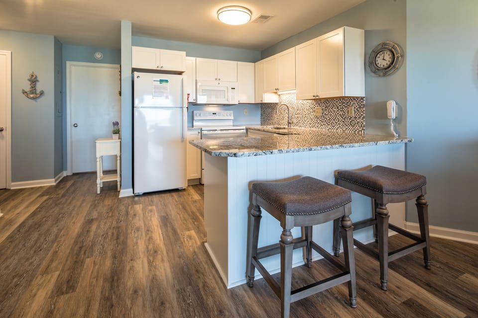 White cabinetry and ample counter space keep everything light and functional, while the breakfast bar with seating invites casual meals and conversation.