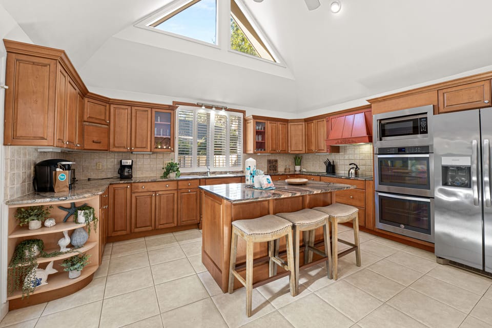 High ceilings and skylights illuminate the chef's kitchen, complete with stainless appliances and rich wood cabinetry.