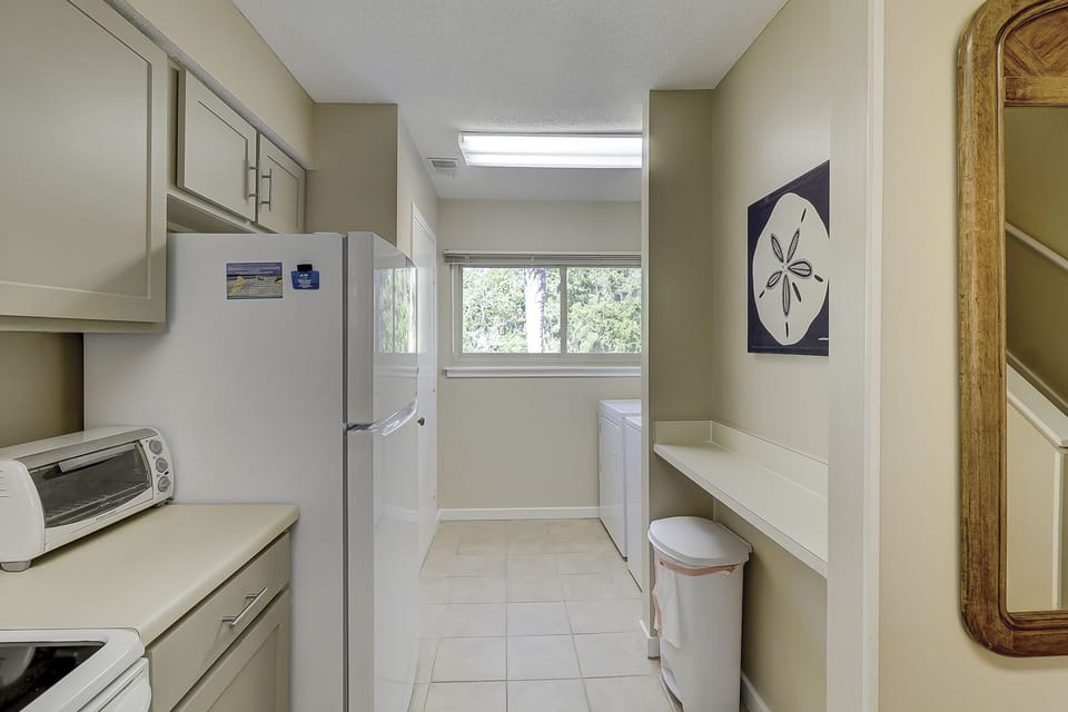 This functional laundry area offers added convenience with full-size washer and dryer, extra counter space for folding, and overhead cabinetry for storage.