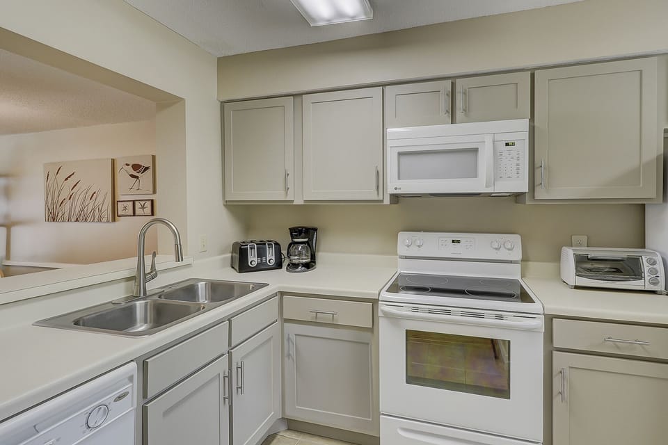 This well-appointed kitchen offers a clean, functional layout with granite countertops, white cabinetry, and full-size appliances.