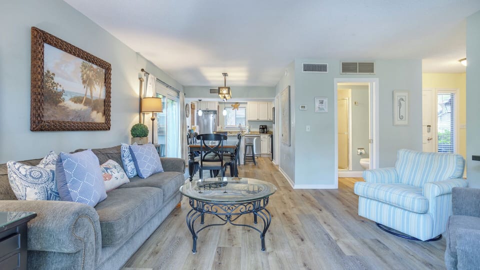 This open dining and living area flows seamlessly toward a wall of windows and sliding glass doors, creating a bright, airy feel throughout.