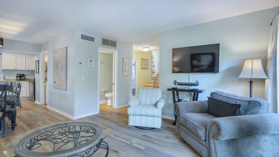 This bright, inviting living area features comfortable seating arranged around a central coffee table, creating a relaxed space for gathering or unwinding.
