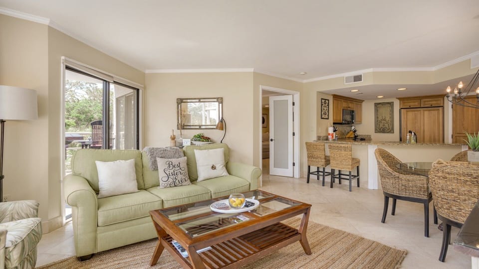 Natural light pours in through oversized windows and sliding glass doors, creating a seamless flow to the outdoor balcony.
