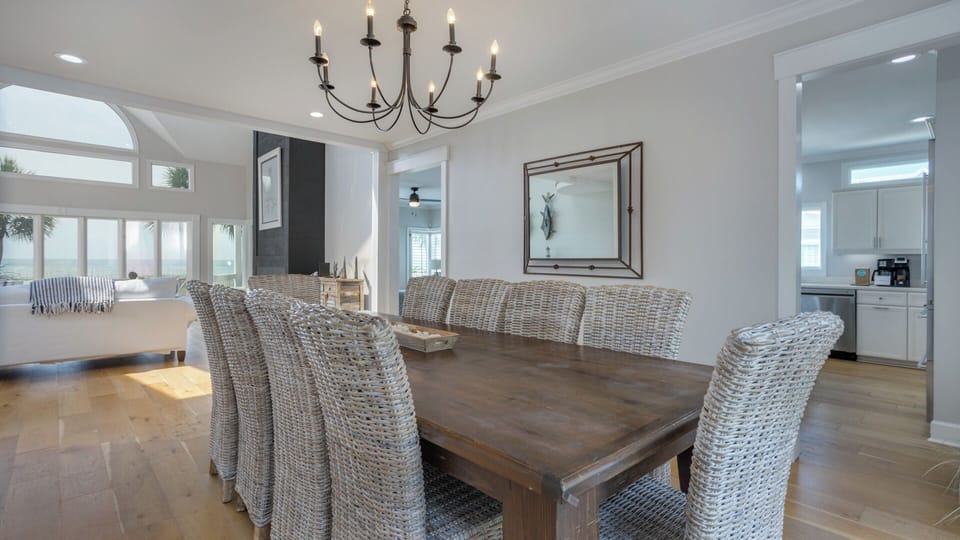 The substantial wood table is paired with woven coastal-style chairs, creating a relaxed yet refined setting for family meals and entertaining.