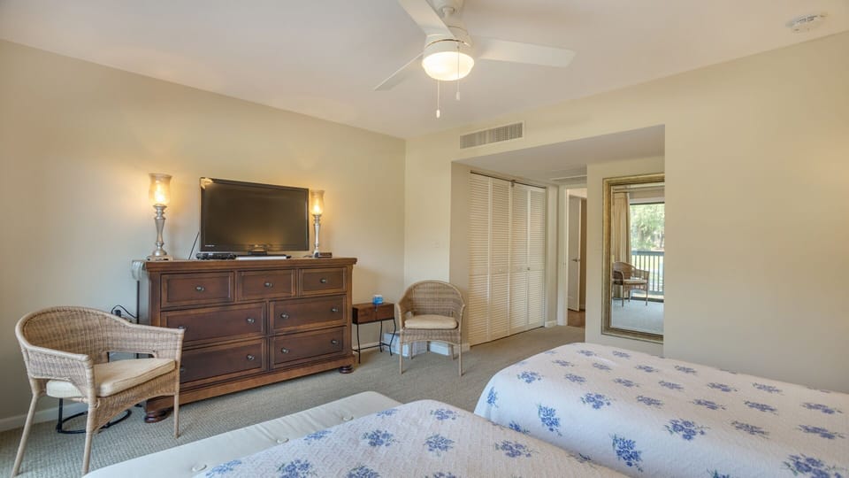 This bright and comfortable guest bedroom is designed for easy relaxation, featuring two twin beds and soft neutral tones throughout