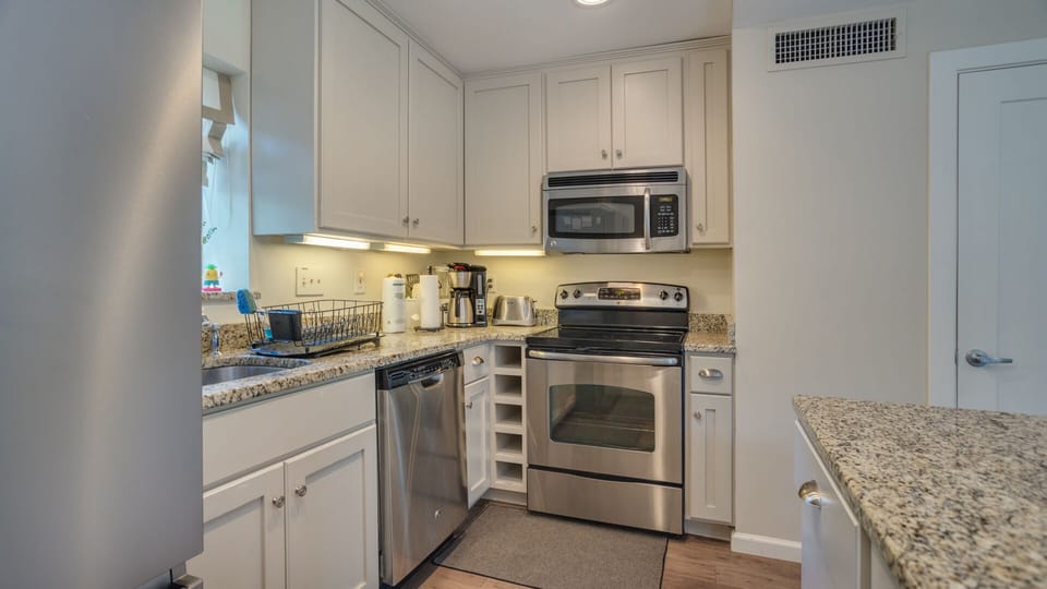 This well-appointed kitchen blends style and function with crisp white cabinetry, granite countertops, and stainless steel appliances.