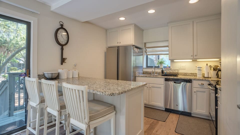 A spacious breakfast bar with seating invites casual meals and conversation, while recessed lighting keeps the space bright and welcoming.
