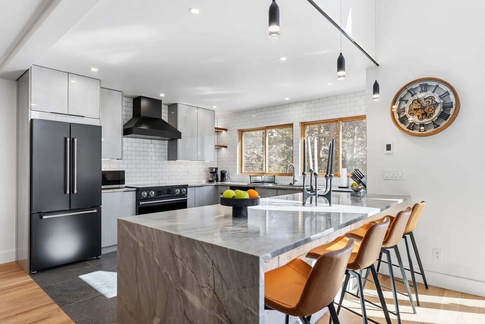 Your culinary dreams come alive in this stunning modern kitchen with gleaming marble island, premium stainless steel appliances, and warm leather seating.