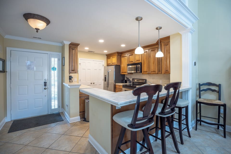 This well-appointed kitchen offers a functional layout with warm wood cabinetry, ample counter space, and a convenient breakfast bar with seating for casual dining.